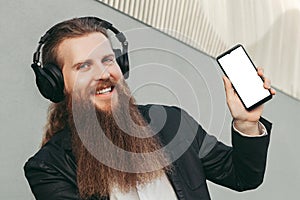 Bearded man in headphones and with phone