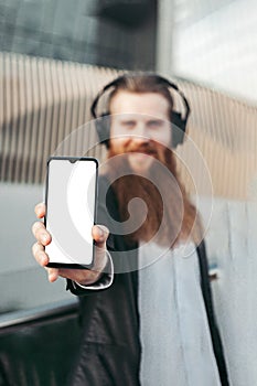 Bearded man in headphones and with phone