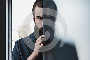 Bearded man hiding by frosted glass