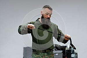 A bearded man in his 40s, a military medic demonstrates a combat medical tourniquet to stop blood during first aid