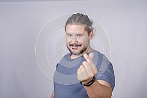A bearded man in his 30s makes a heart finger gesture. Smiling expressive his fondness photo
