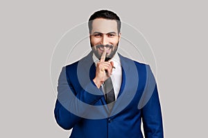 Bearded man holding finger near lips showing shh gesture, keeping secrets preparing surprise.