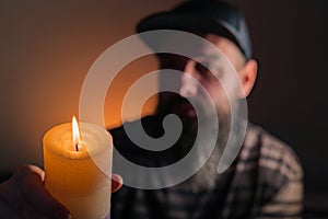 Bearded man holding a lit candle in his hand. Orange background