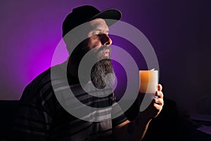 Bearded man holding a lit candle in his hand. Pink background.