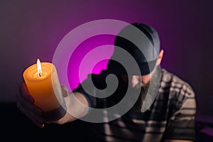 Bearded man holding a lit candle in his hand. Pink background