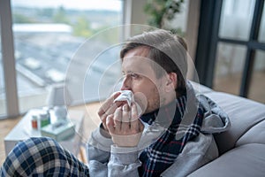 Bearded man holding napkin while having stuffy nose