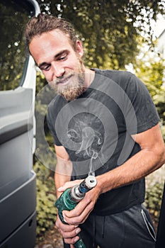 Bearded man holding a smoking power drill