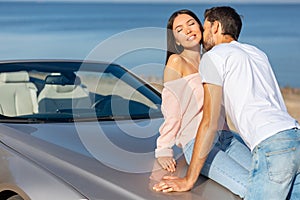 Bearded man kissing his girlfriend leaning the car