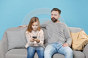 Bearded man in knitted sweater with cute child baby girl. Father little daughter isolated on pastel blue background