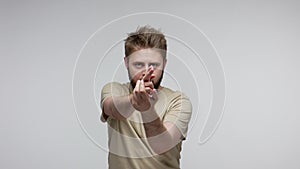 Bearded man looking around for target pointing finger gun gesture and choosing you at camera, shooting killing
