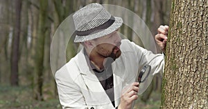 Bearded man looking at green moss through loupe