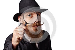 Bearded man looking through a magnifying glass.