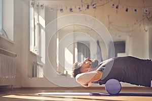 Bearded man lying on foam roller during training in studio