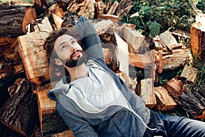 Bearded man lying on pile of wood and dreaming