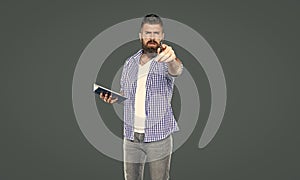 bearded man making notes in book point on you