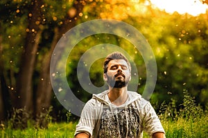 A bearded man is meditating on green grass in the park