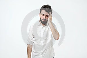 Bearded man with messy hair and beard, rubbing head and being tired or having hangover