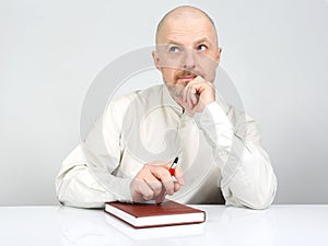 Bearded man with a notebook and a pen in his hands thinks