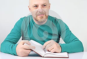 Bearded man with a notebook and a pen in his hands thinks