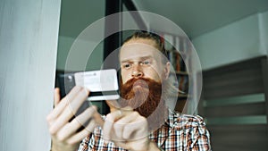 Bearded man online shopping and banking with credit card using smartphone at home