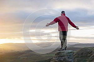 Bearded Man in orange jacket relaxing alone on the top of mountain and drinking hot coffee at sunrise. Travel Lifestyle