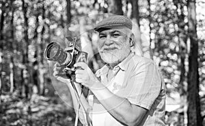Bearded man outdoors. Pensioner enjoy summer day. Man with old vintage camera in hands. Take photos nature. Lifestyle