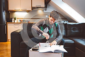 Bearded man physics student sitting on the sofa studying at home