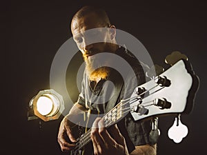 Bearded man playing bass guitar with spotlight