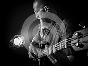 Bearded man playing bass guitar on stage