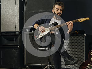 Bearded man playing an electric guitar in a studio