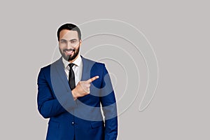 Bearded man pointing finger away with toothy smile on face, empty space for your advertisement.