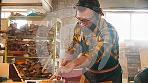 Bearded man in protective glasses cutting a piece of wood with a circular saw