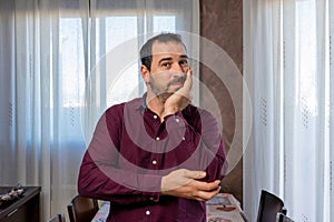 Bearded man in a purple shirt leaning his face on his hand with resignation