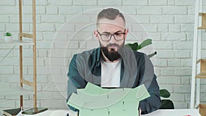 Bearded man put on his eyeglases and start to works at the computer