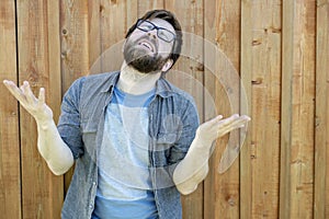 A bearded man raises his palms and head up and makes a moan. Emotions of despair and problems. Isolated on the background of an