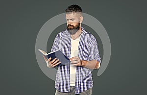 bearded man reading book on grey background