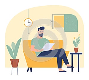 Bearded man reading on a yellow sofa in a cozy room with plants and clock. Casual male relaxing with paperwork at home