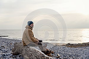 Bearded Man relaxing alone on seaside on cold winter day. Travel  Lifestyle concept