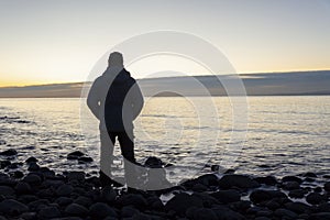 Bearded Man relaxing alone on the seaside and making a timelapse on the phone on cold winter day at sunset. Travel  Lifestyle