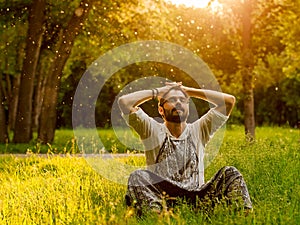 A bearded man is relaxing on green grass in the park