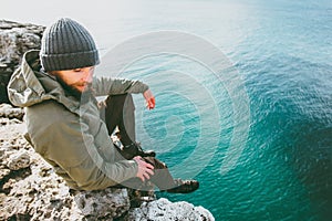 Bearded Man relaxing on rocky cliff alone thinking