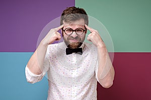 Bearded man in round glasses is trying to remember something, he is trying very hard to gather his thoughts.