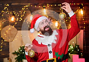 Bearded man Santa Claus decorating christmas tree with golden decorations. Winter decorations. Shimmering balls