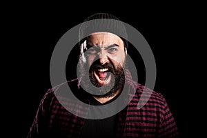 Bearded man screaming in anger on black background