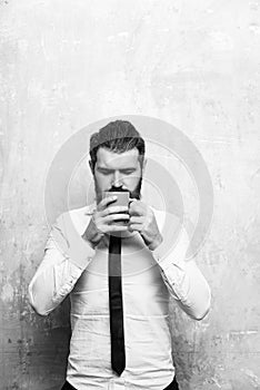 Bearded man with serious face drink tea from coffee cup