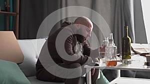 Bearded man in severe depression drinking alcohol at home. abuse and alcoholism concept.