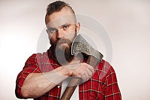 Bearded man shaving with an axe on black background