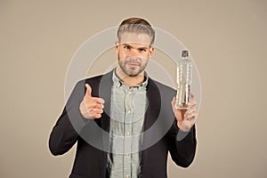 Bearded man show thumbs up to bottle of water. Thirsty businessman with beard in blue shirt and coat. Thirst and