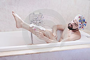 Bearded man in shower cap relaxes with shave in bath time. Skin and self-care concept, men& x27;s health is matters