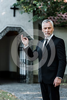 Bearded man showing ok sign near church